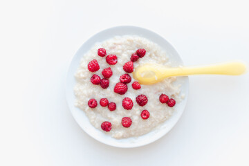 porridge with berries on a white plate, oatmeal with raspberries, baby porridge 