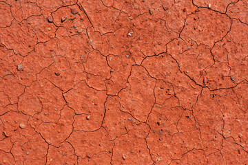 Red dried cracked soil. The soil is covered with red dust from iron ore.