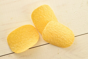 Several potato chips on a wooden table, close-up, top view.