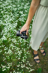 Unrecognizable woman hold digital camera in her hands on flower field landscape
