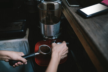 The barista is taking the finished coffee out of the grinder. Then take the coffee to compress to add flavor. before importing the next coffee machine.