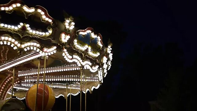 Vintage carousel lights in the park, spinning retro merry-go-round in the evening in summer.