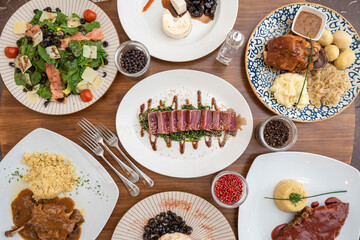 Dishes of international gastronomy. Red tuna tataki, bbq ribs, confident duck, pork with sauerkraut, salmon and spinach salad.