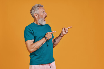 Surprised senior man pointing copy space and making a face