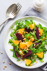 Salad of arugula, baked beetroot, orange and red onions with spices and pine nuts in awhite dish....