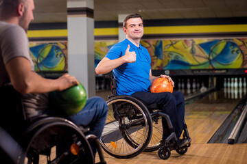 Two young disabled men in wheelchairs playing bowling in the club
