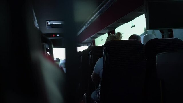 Tourist passengers seated inside bus cabin during travel rear view