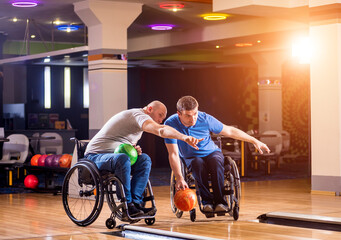 Two young disabled men in wheelchairs playing bowling in the club