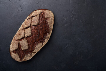 Freshly baked homemade bread on artisan sourdough rye on black stone or concrete background. Top view. Food cooking background. Copy space.