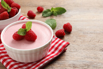 Delicious raspberry mousse with mint on wooden table, space for text