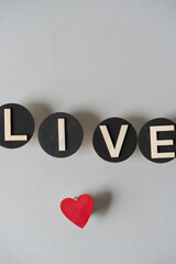 live in plain wood letters on black discs and a hand painted red heart