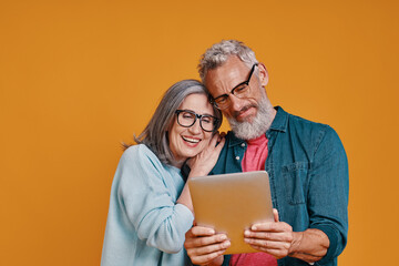 Happy senior couple smiling and using digital tablet and smiling