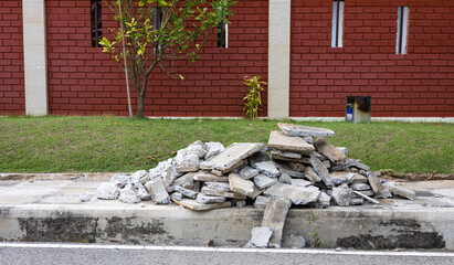 A pile of concrete rubble near a brick wall.