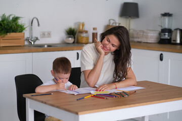 Fototapeta premium little boy learns to draw. Mom and son have fun drawing with pencils. Children's creativity.