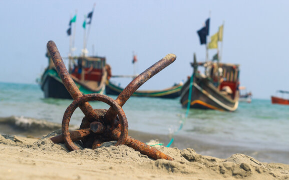 A fishing boat anchored by the beach in St. Martin's Island, Bangladesh. Fishing boat rusty traditional anchor on a beach by the sea. Rusty anchor wet beach sand and wave.