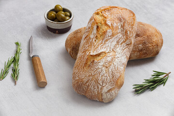 Artisan sourdough ciabatta bread with olives and rosemary on a concrete table. Freshly baked...