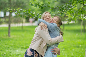 Fototapeta premium happy mother with her daughter hugging a teenager in the summer. Caring happy mother enjoy day with teenage girl child, laugh have fun. Mother giving her daughter advice.