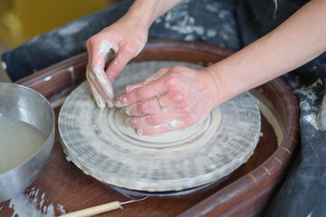 Close up female hands make dishes from clay. woman hands working on potters wheel. The master potter works in a workshop