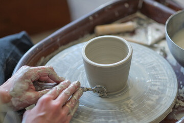 Close up female hands make dishes from clay. woman hands working on potters wheel. The master potter works in a workshop