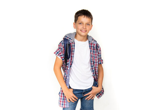 Boy Teenager 11 Years Old Schoolboy Looking At Camera On White Background With Backpack And Smiling. Dressed In Plaid Shirt And White T-shirt