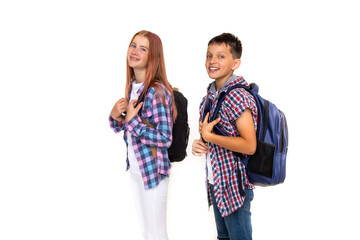 Boy and girl teenager 11 years old schoolboy and schoolgirl looking at camera on white background with backpack and smiling. Dressed in plaid shirt, white shirt