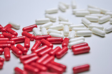 Many white and red capsule pills on a colorful background. Health supplements and medicines