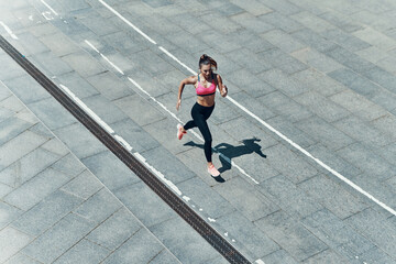Top view of attractive young woman in sports clothing running outdoors
