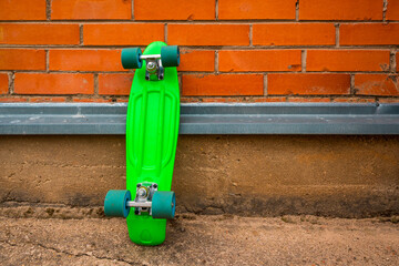 Green skateboard leaning against brick wall © graja
