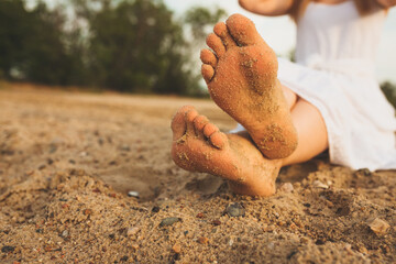 Women's feet on the yellow sand by the sea. The concept of travel