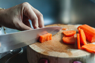 Carrots are being cut on the wooden chopping board.