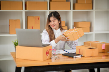 Fototapeta na wymiar Small Business SME entrepreneur of Young Asian women working with laptop for Online shopping at home,Cheerful and Happy with box for packaging in home,Own Business Start up for Online shopping