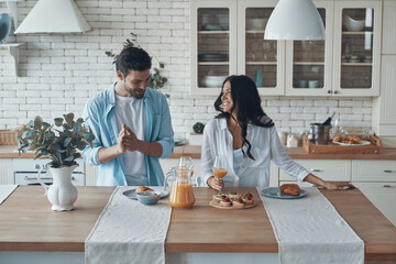 Happy young couple preparing breakfast together while spending time in the domestic kitchen