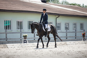 man rider and black stallion horse trotting fast during equestrian dressage competition in summer