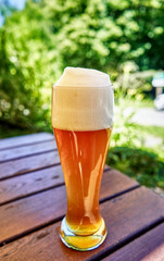 Head of foam on glass filled with wheat beer against blurred background, selective focus