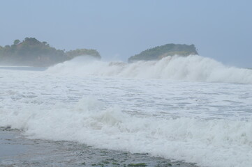 Close-up view of sandy beach and waves in the sea on a sunny day.