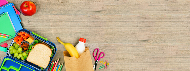 Healthy school lunch and school supplies. Corner border, top view on a wood banner background.