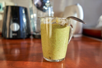 Spoon on top of cup with a healthy green smoothie. 