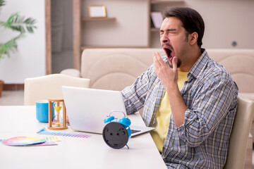 Young male freelancer in time management concept at home