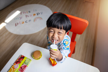 Close-up portrait Asian child boy straight black hair wearing a white pajamas with blue stripes looking at camera of him make funny faces of happy smiling. Advertising childrens products