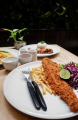 Close up delicious food menu of catfish and chips with sliced vegetables