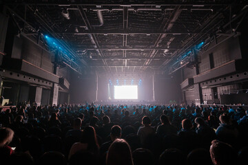 Audience sitting in front of stage with screen