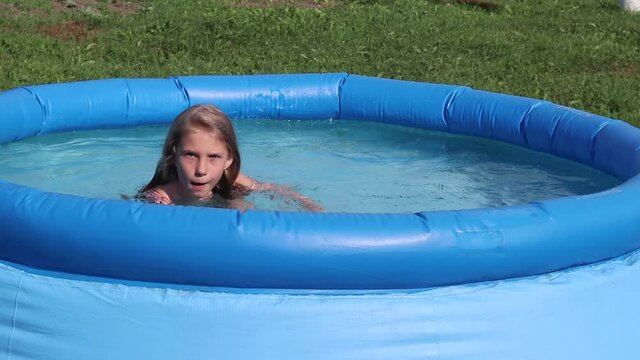 Natural lighting. bright sun. A girl in a swimsuit is swimming in a small pool. Close-up.