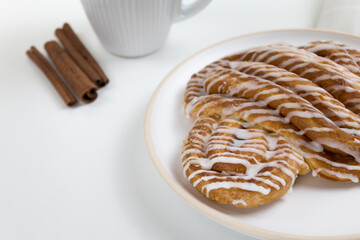 Cinnamon roll or cinnamon bun Dessert on plate with white cup of coffee. Classic American or French bakeries. 