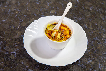 Isolated Crème  brulée , creme brulée, with natural vanilla beans in ramekins with spoons and lined up in depth of field blur