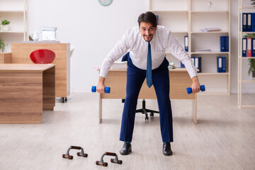 Young male employee doing sport exercises during break