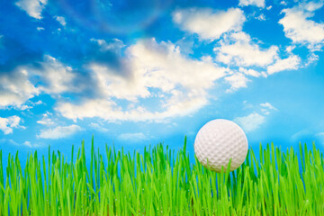 Golf ball on a green lawn against a blue sky with clouds.