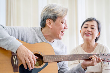 Elderly couple singing a song while playing guitar