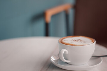 Latte art hot coffee in the morning at a cafe with vintage light as blue background.