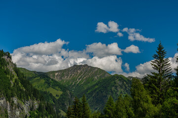 Summer valley with Grossarler Ache small river and blue cloudy sky