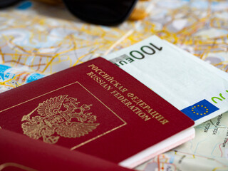 A close-up of a Russian passport with embedded euro bills is on the map. The concept of travel and recreation